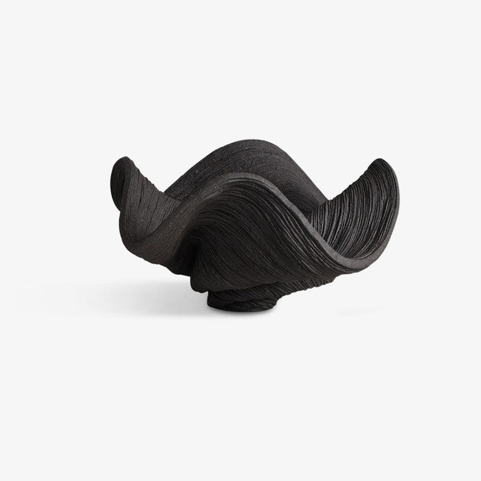 Small coiled black porcelain bowl with a dynamic wavy shape and intricate horizontal lines from a slightly different