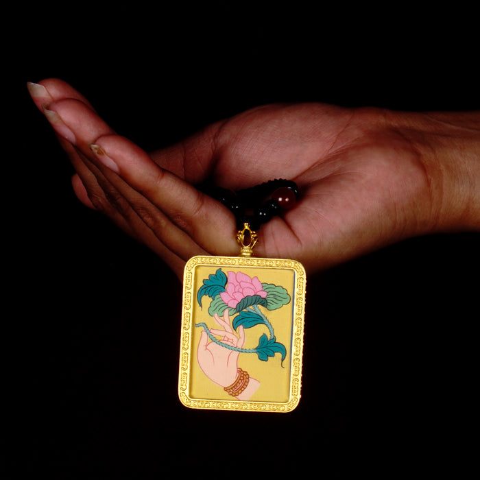 Hand holding lotus Ghau Thangka locket with hand-painted symbolic artwork inside traditional Himalayan amulet Nepal