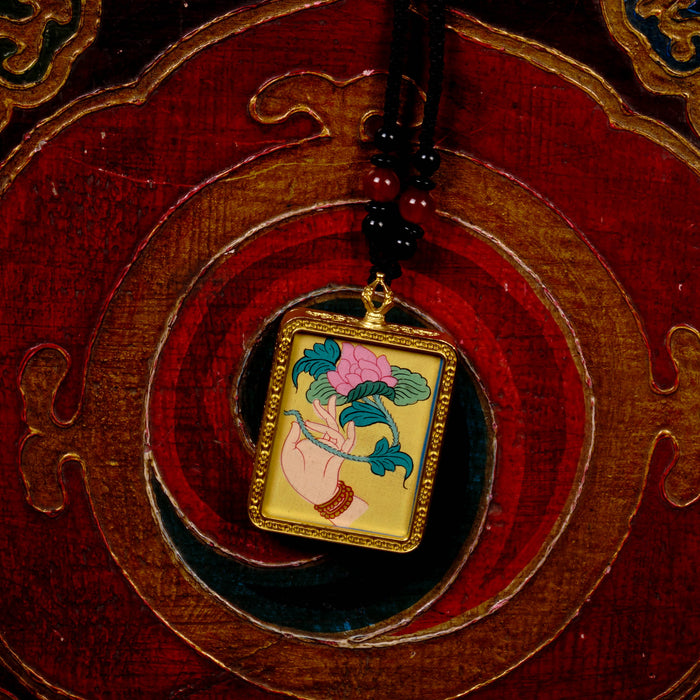 Hand holding lotus Ghau Thangka locket with hand-painted symbolic artwork inside traditional Himalayan amulet Nepal